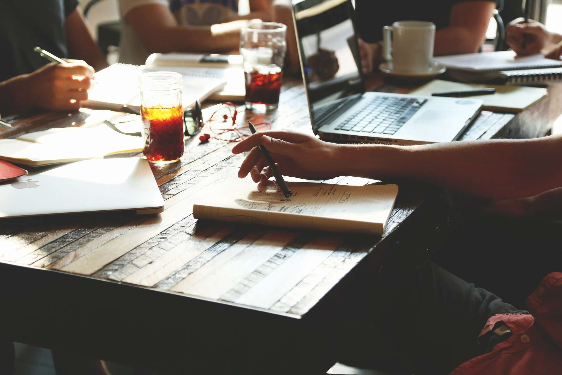 Abbildung von einem Schreibtisch, auf dem Arbeitsmaterialien, Getränke und ein Laptop stehen